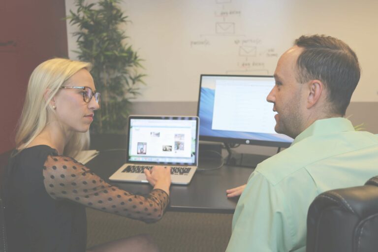 A woman reviewing design mockups for a custom website on a laptop during a feedback session.