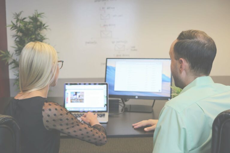 Web support specialists reviewing website performance on multiple screens with a client.