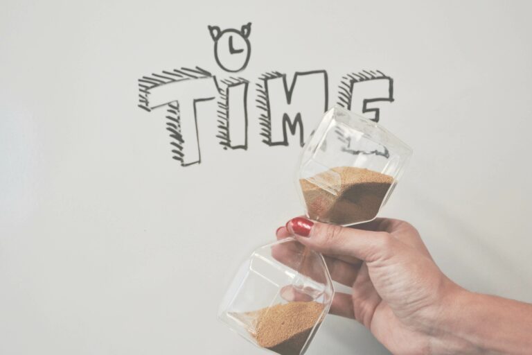 Close-up of a hand holding an hourglass, symbolizing time management in web design projects.