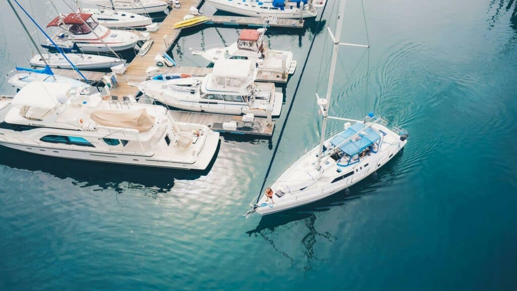 Mobile optimized aerial view of luxury yachts and sailboats docked at marina with turquoise water