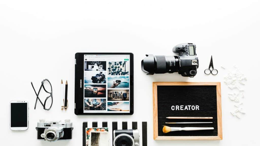 Flat lay of creative tools including cameras, tablet, and accessories for local customer acquisition