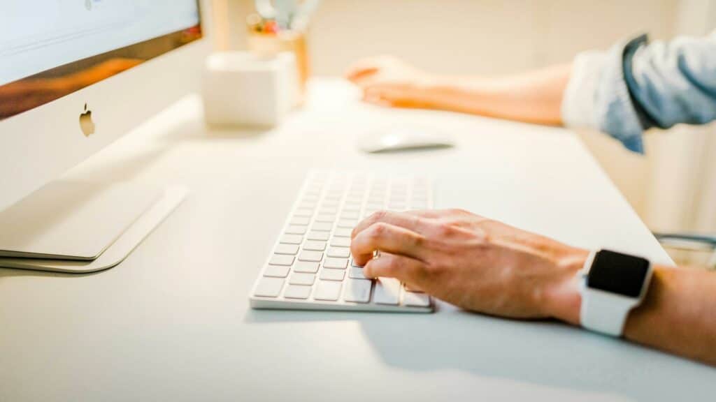 Targeted email marketing specialist working on Apple computer with smartwatch, demonstrating modern digital marketing workspace