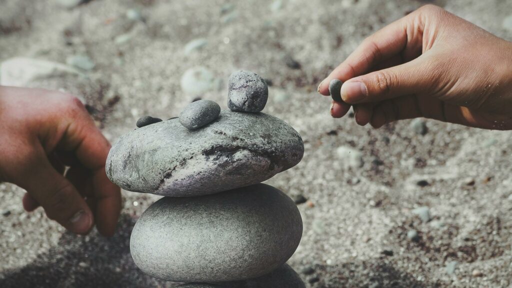 Hands stacking stones on a sandy surface, symbolizing balance and creativity in web design London