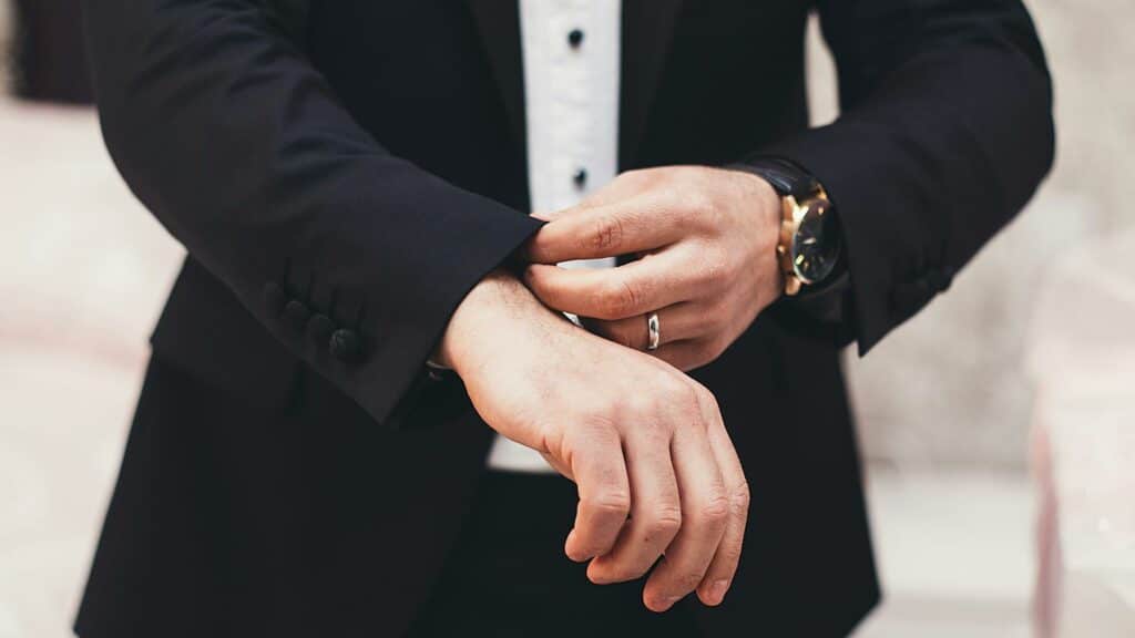 Man adjusting suit sleeve with watch and ring