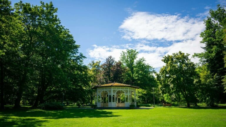 A gazebo in a lush green park under a blue sky