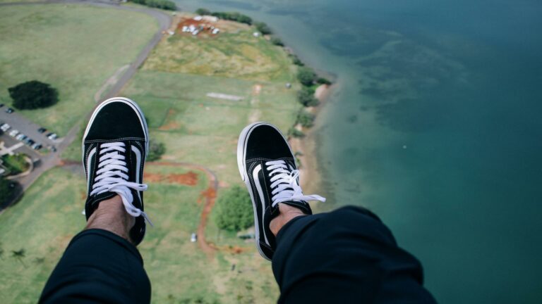 Feet wearing black and white sneakers dangling over a landscape