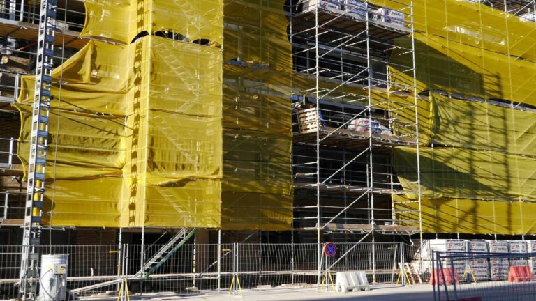 Scaffolding covered with yellow safety netting at a construction site for long-tail keyword usage.