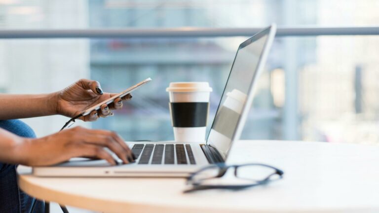 Person analyzing data on laptop with coffee and glasses on desk