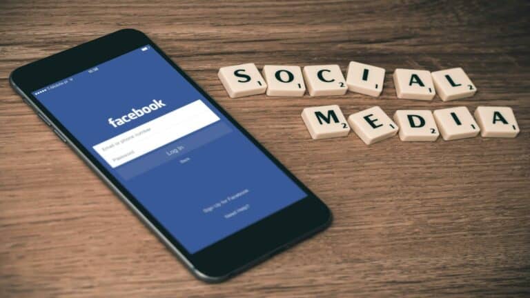 Smartphone displaying Facebook login screen alongside scrabble tiles spelling 'Social Media' for local search optimization