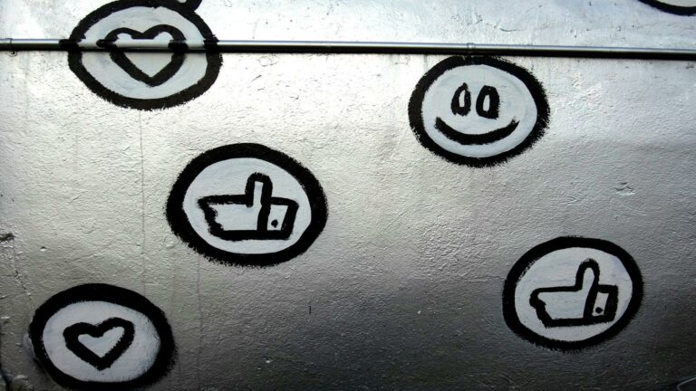 Social media icons artwork showcasing heart, smiley face, and thumbs-up symbols on a metallic wall background