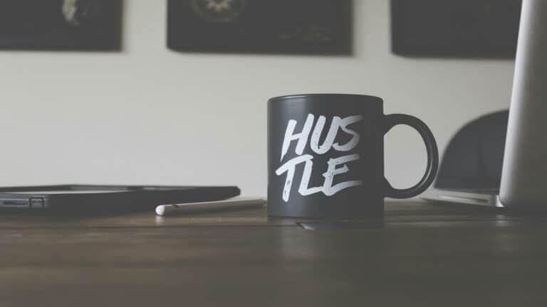 Black mug with 'Hustle' text on a desk