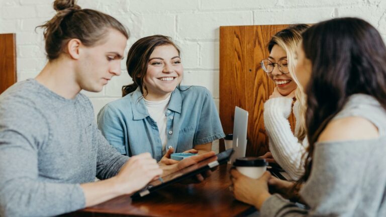 Group of people discussing around a table with laptops and tablets