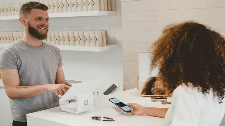 Two people engaging in a point-of-sale transaction with Square payment system in a bright retail space