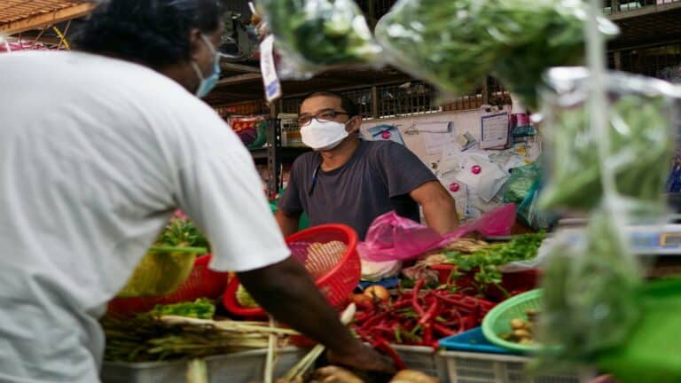 A vendor discussing business marketing strategies at a vibrant market stall with fresh produce.