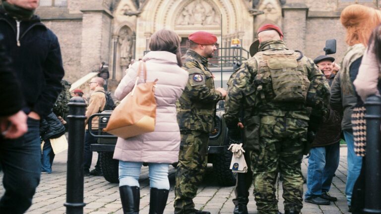 Website design company team meeting military personnel in camouflage uniforms and red berets gathered outside historic gothic church entrance