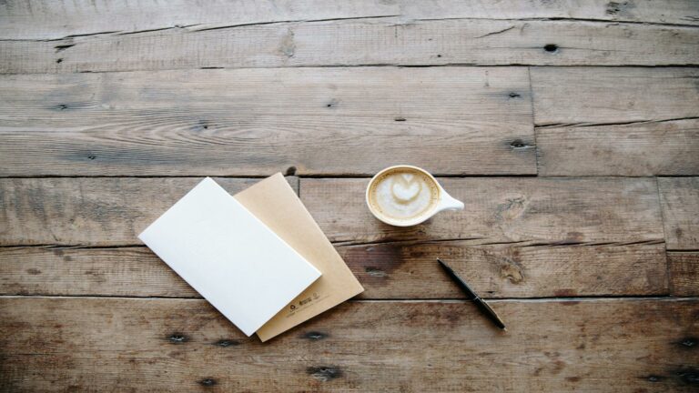 Content creation services workspace with coffee, notebook, and pen on a wooden desk