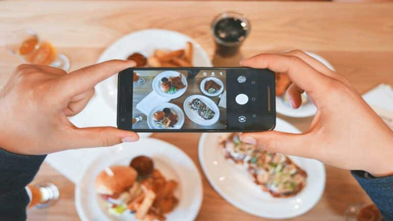 Hands holding a smartphone capturing food for video content marketing