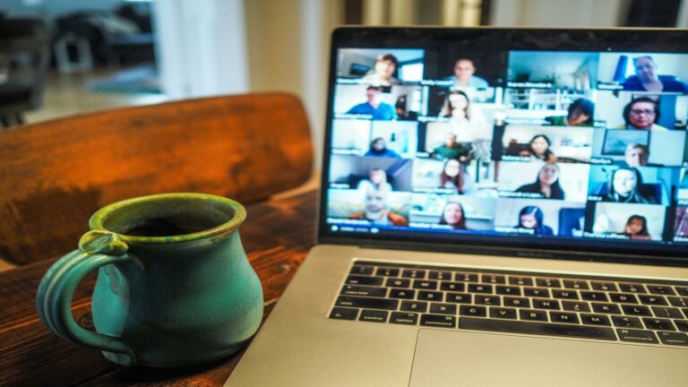 Mobile web design in a virtual meeting setup with a coffee mug on a wooden table