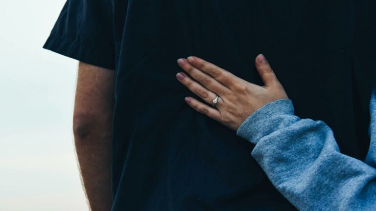 Hand with a ring placed on a person's back symbolizing connection and creativity for creating engaging content