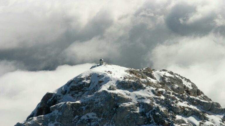 A small shelter on a snowy mountain peak surrounded by clouds