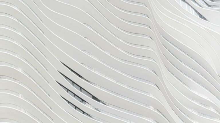 Minimalist white architectural facade with curved wave-like patterns and integrated window design