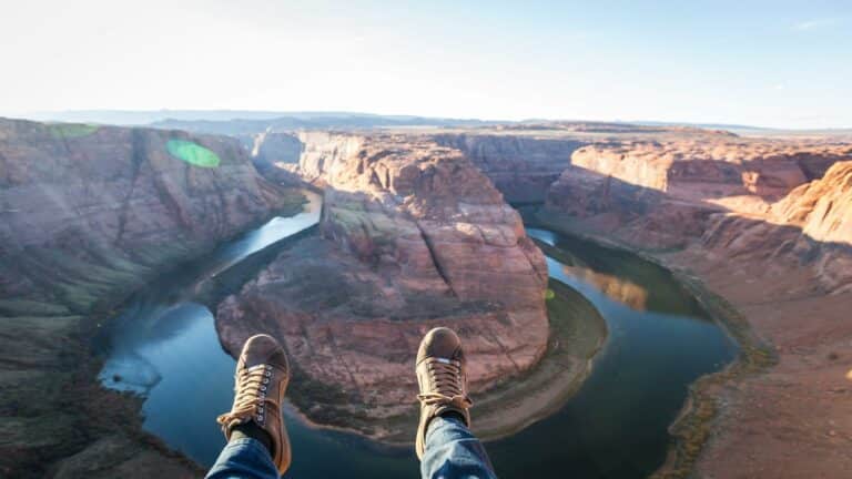 View of a canyon with a river and feet in the foreground