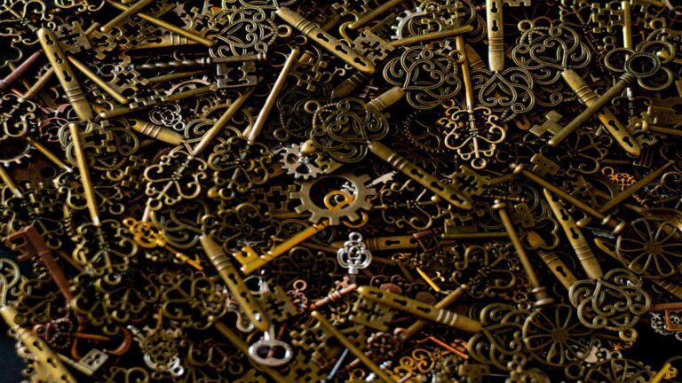 Artistic arrangement of antique brass and copper keys with ornate designs and mechanical gears on dark background