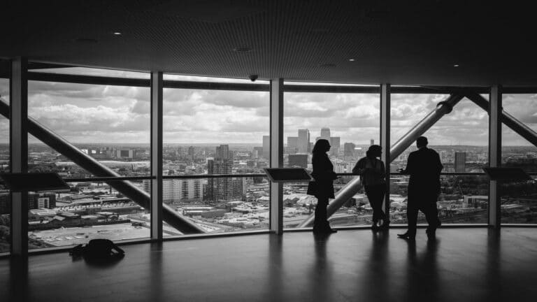 Silhouettes of people in a high-rise building with a city view