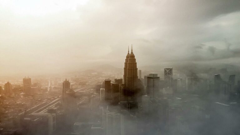 Target local customers in Kuala Lumpur - Iconic Petronas Towers emerging through morning mist in urban Malaysia skyline