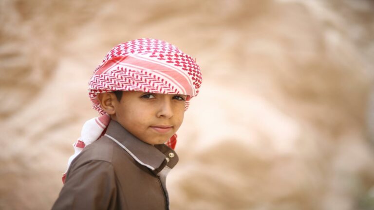 Young boy wearing a red and white keffiyeh, representing cultural heritage, perfect for improving bounce rate through visual engagement.