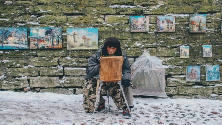 Street artist displaying paintings for search engine rankings optimization in snowy urban setting