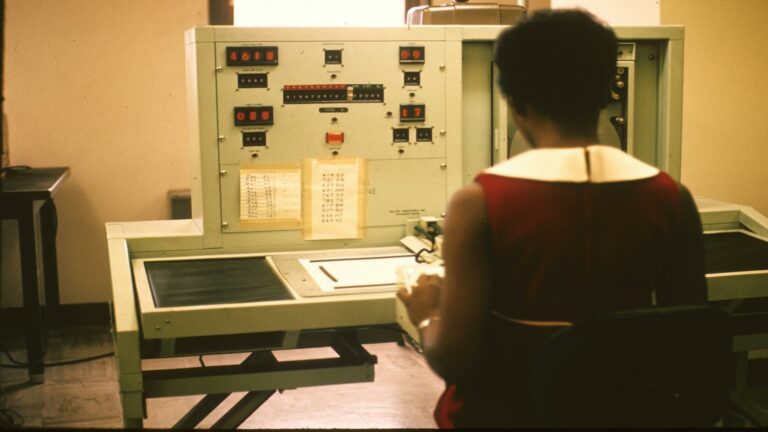 A person operating a vintage computing machine in a laboratory setting.