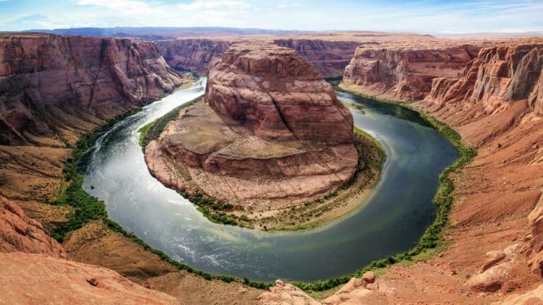 Aerial view of Horseshoe Bend with the Colorado River curving around a massive rock formation surrounded by desert cliffs.