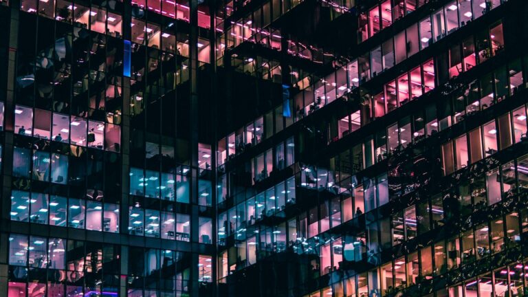 Exterior view of a modern office building with colorful lights at night