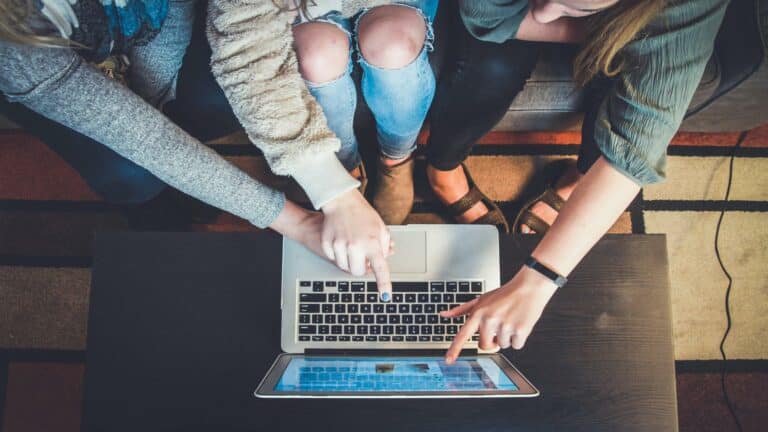 Group of people pointing at a laptop screen while discussing strategies.