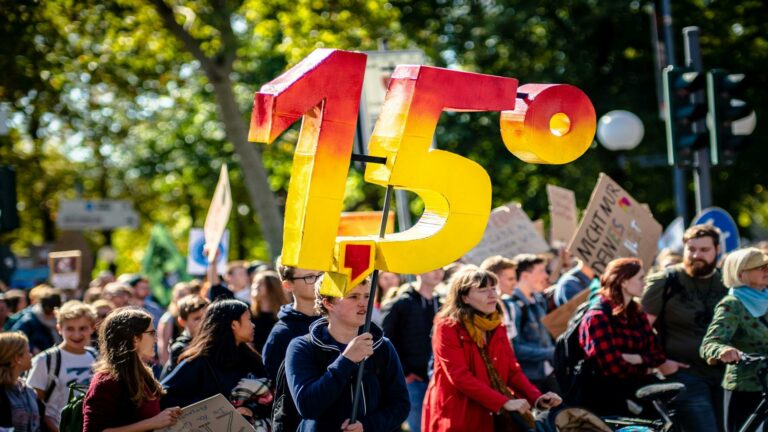 Protesters holding a 1.5 degree sign at a climate march, symbolizing digital marketing trends