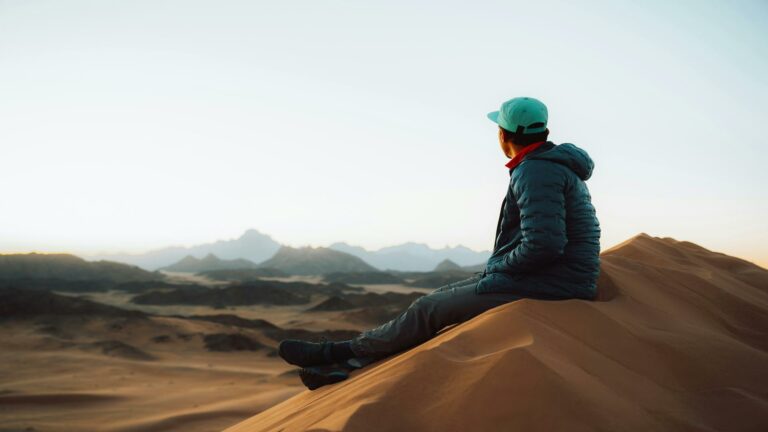 Person sitting on a sand dune at sunrise, symbolizing the vast opportunities of Local SEO techniques