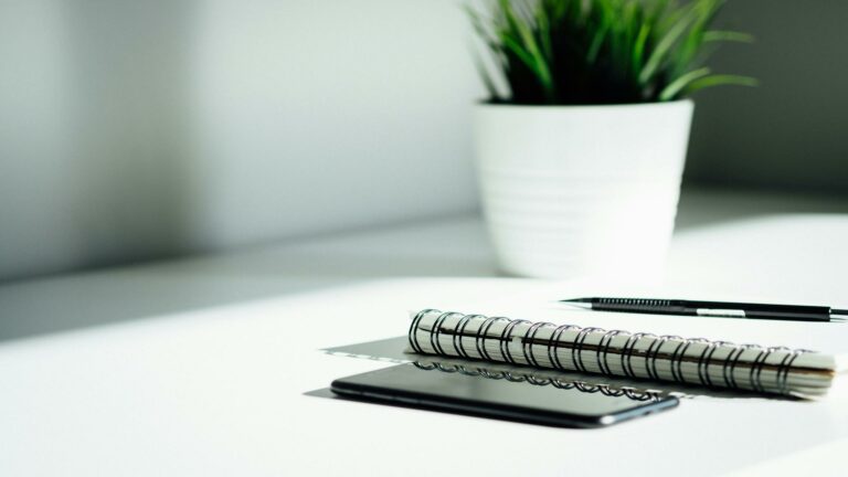 Website redesign tips: minimalist desk setup with spiral notebook, smartphone and potted plant for web planning