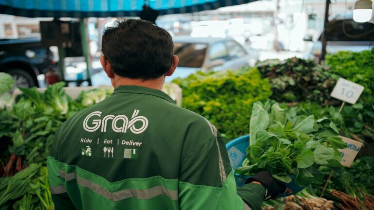 Grab delivery person selecting fresh greens at a market