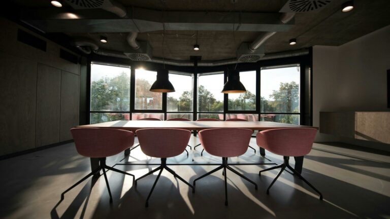 A modern conference room with large windows and pink chairs