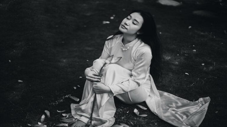 A black-and-white photo of a woman in traditional clothing holding a lotus flower.