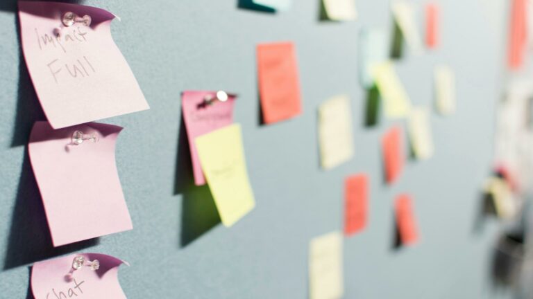 Colorful sticky notes pinned on a board with words written on them.