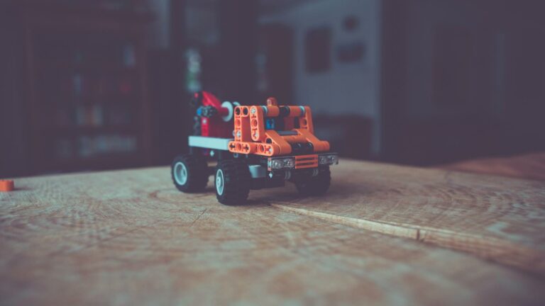 Close-up of orange toy construction crane on wooden surface with blurred background