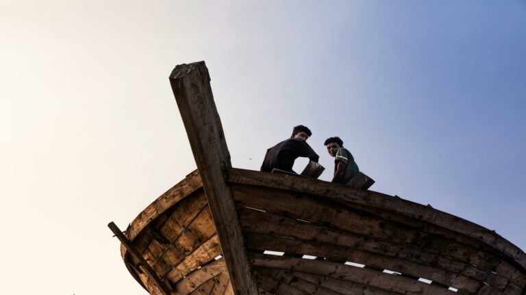 Two men working on a wooden structure against the sky