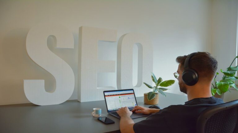 Professional working on SEO optimization with laptop, headphones, and decorative SEO letters in background