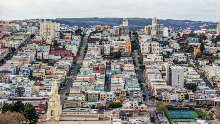 Aerial cityscape of San Francisco showing grid street pattern, residential buildings, and iconic church spire