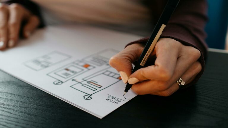 A person sketching website security goals and structure on paper.