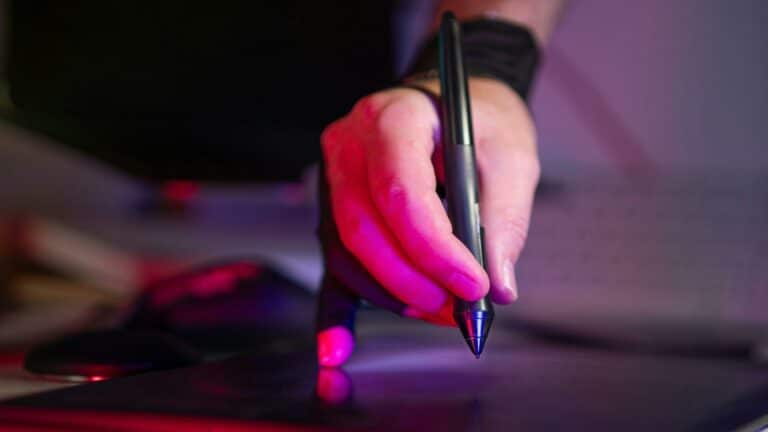 Hand using a digital pen on a tablet with vibrant lighting