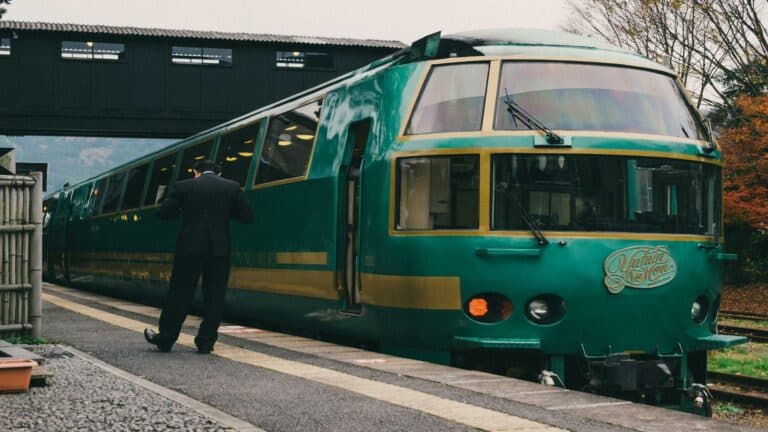 Luxury green and gold vintage train with conductor boarding at platform