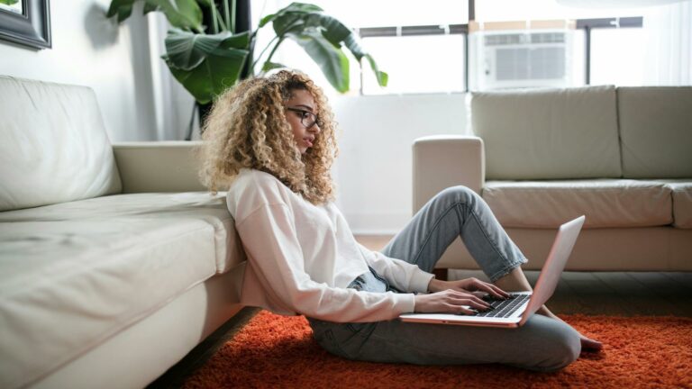 Woman sitting on the floor with a laptop, designing a local website